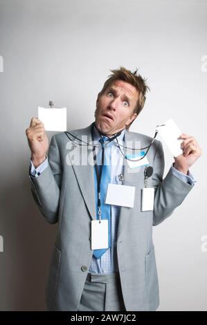 Verwirrt Büroangestellter indundated mit leeren Namensschilder, mit einem lustigen Ausdruck bei einem leeren Platz kopieren Stockfoto