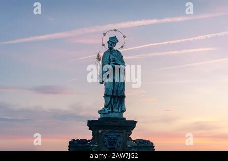 Nahaufnahme der Statue des Johannes von Nepomuk auf der Karlsbrücke in Prag mit farbenfrohem Sonnenaufgang auf dem Hintergrund Stockfoto