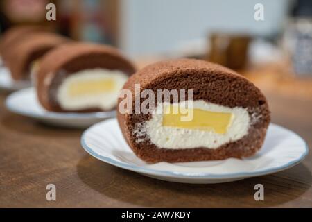 Köstliche Schokoladenkuchenrolle mit Sahne und Mango-Pudding. Aufgesetzte Schokoladenkuchenrolle. Stockfoto