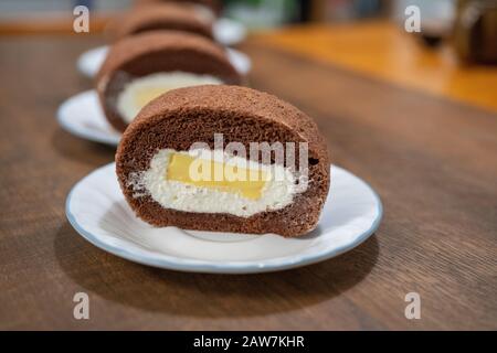 Köstliche Schokoladenkuchenrolle mit Sahne und Mango-Pudding. Aufgesetzte Schokoladenkuchenrolle. Stockfoto
