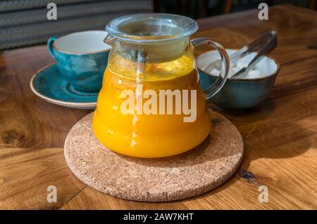 Meeresbuckdornbeere Tee-Infusion in Glas-Teekanne mit Teelbecher und Zuckerschüssel mit Zuckerzange. Kräutermedikament Tee auf dem Tisch Stockfoto