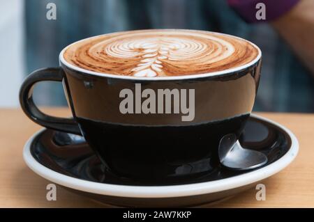 Nahaufnahme der Kaffeetasse mit Cappuccino-Kaffee und Milchschaum. Hintergrund für Kaffeetasse Stockfoto