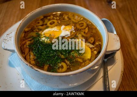 Traditionelle Rassolnik-Suppe in einer rustikalen Schüssel, garniert mit saurer Sahne und Dill Stockfoto