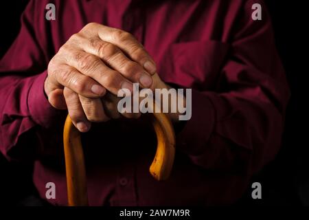 Älterer Mann ruht seine Hände auf seinem Gehstock Stockfoto