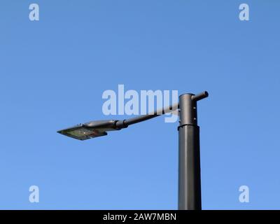 Moderne LED-Straßenleuchte mit eckigem Kopf, klarer blauer Himmel. Abstrakte Low-Angle-Ansicht in abnehmender Perspektive im Taglicht. Ligting Technology Konzept Stockfoto