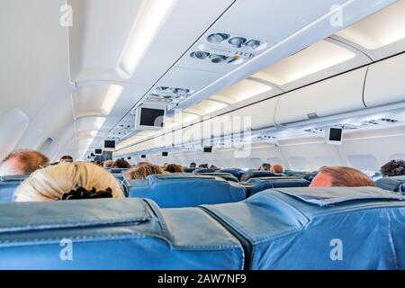 In einer Flugzeugkabine - Passagiersitze während des Flugs - Reihen mit Passagierköpfen von hinten. Stockfoto