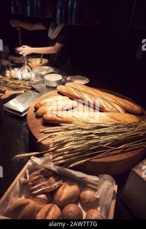 Frisch gebackenes traditionelles Brot auf Holztisch mit Backwaren für Frauen im Hintergrund Stockfoto