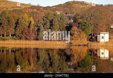 Duddingston, Edinburgh, Schottland, Großbritannien. Februar 2020. Kühle Temperatur von -1 Grad, Reflexionen über Duddingston Loch von Thomson's Tower und Dr. Neil's Garden mit Duddingston Kirk. Thomson's Tower wurde von William Henry Playfair entworfen und im Jahr 1825 für die Duddingston Curling Society zur Lagerung ihrer Steine gebaut. Das obere Stockwerk war sowohl ein Treffpunkt für die Lockenstab als auch ein Atelier für den angesehenen Künstler The Rev. John Thomson, Minister von Duddingston von 1805 bis 1840. Stockfoto