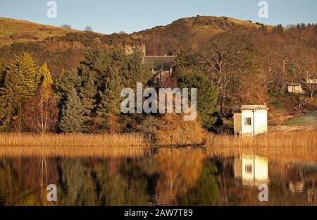 Duddingston, Edinburgh, Schottland, Großbritannien. Februar 2020. Kühle Temperatur von -1 Grad, Reflexionen über Duddingston Loch von Thomson's Tower und Dr. Neil's Garden mit Duddingston Kirk. Thomson's Tower wurde von William Henry Playfair entworfen und im Jahr 1825 für die Duddingston Curling Society zur Lagerung ihrer Steine gebaut. Das obere Stockwerk war sowohl ein Treffpunkt für die Lockenstab als auch ein Atelier für den angesehenen Künstler The Rev. John Thomson, Minister von Duddingston von 1805 bis 1840. Stockfoto