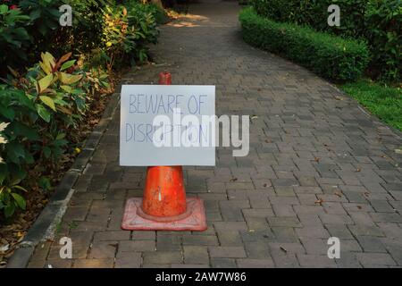 Kartonschild mit Handschrift Lesen Vorsicht vor Störungen, die auf dem Gehweg im Garten angebracht sind, störendes Geschäftskonzept Stockfoto