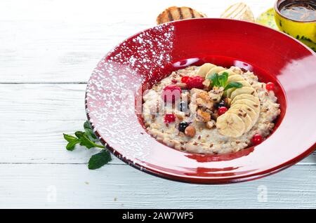 Haferbrei mit Nüssen, Bananen und wilden Beeren. In der Platte. Draufsicht. Flache Laienzusammensetzung Freier Kopierspeicher. Stockfoto