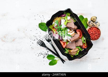 Kalbfleisch mit Kartoffeln, Gemüse und grünen Erbsen. Lebensmittel mit Lieferung. Draufsicht. Freier Speicherplatz für Ihren Text. Rustikaler Stil. Stockfoto