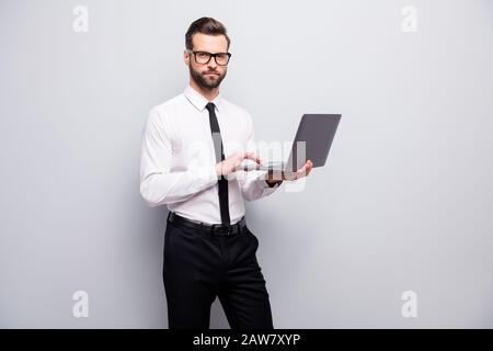 Streng fokussierter Immobilienmakler Chef Mann halten Laptop verwenden moderne Technologiearbeit an seinem Projekt Workshop Training tragen weißes Hemd schwarze Hosen Stockfoto