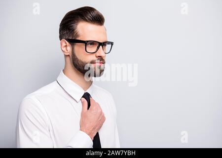 Nahaufnahme eines gutaussehenden jungen Macho-Geschäftsmannes, der sich auf ein Geschäftstreffen vorbereitet, um die elegante schwarze Krawatte zu fixieren. Tragen Sie das weiße Bürotrikot in Schwarz Stockfoto
