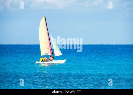 Segelboote am schönen kubanischen Strand von Varadero. Ein Segelschiff transportiert Touristen bei gutem Wetter über das blaue Meer. Touristenkatamaran. Eco Stockfoto