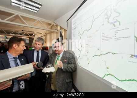 07. Februar 2020, Rheinland-Pfalz, Koblenz: Arno Trauden (l-r), Geschäftsführer des Landesbetriebs Mobilität, Steffen Bilger (CDU), Parlamentarischer Staatssekretär im Bundesverkehrsministerium, Und Andy Becht (FDP), Staatssekretär für Verkehr Rheinland-Pfalz, hält die Kameras, mit denen die Lkw im Rahmen der Inbetriebnahme eines intelligenten LKW-Parksystems auf der AUTOBAHN A61 aufgezeichnet werden. Im Hintergrund sehen Sie die grafische Darstellung des Systems. Das Parkplatzzuweisungssystem für LKWs ist das erste seiner Art in Rheinland-Pfalz und Stockfoto