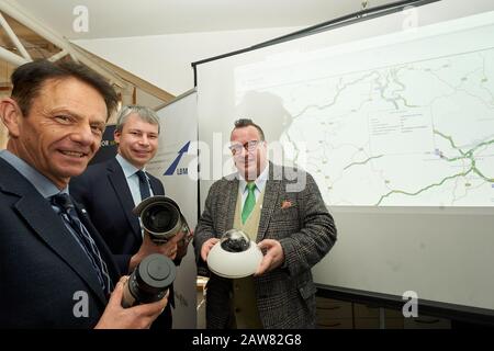 07. Februar 2020, Rheinland-Pfalz, Koblenz: Arno Trauden (l-r), Geschäftsführer des Landesbetriebs Mobilität, Steffen Bilger (CDU), Parlamentarischer Staatssekretär im Bundesverkehrsministerium, Und Andy Becht (FDP), Staatssekretär für Verkehr Rheinland-Pfalz, hält die Kameras, mit denen die Lkw im Rahmen der Inbetriebnahme eines intelligenten LKW-Parksystems auf der AUTOBAHN A61 aufgezeichnet werden. Im Hintergrund sehen Sie die grafische Darstellung des Systems. Das Parkplatzzuweisungssystem für LKWs ist das erste seiner Art in Rheinland-Pfalz und Stockfoto