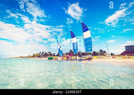 Segelboote ankerten in der Karibik, viele Touristenboote, Kajaks und Katamarane stehen vor dem Hintergrund einer tropischen Insel am Ufer. Stockfoto