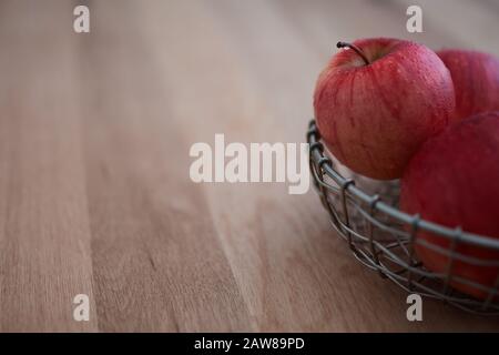 Wasser tropft von einem roten apfel in einem Korb auf Eichholz Stockfoto