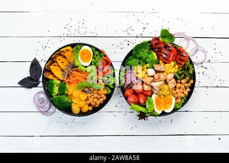 Buddha-Schüssel: Gemüse, Obst und Fleisch in schwarzem Teller auf altem Hintergrund. Herbstgerichte. Draufsicht. Freier Speicherplatz für Ihren Text. Stockfoto