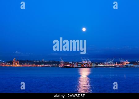 Große Lune mit Pfad auf dem Wasser der Elliot Bay über Seattle Port Night View, WA, USA Stockfoto