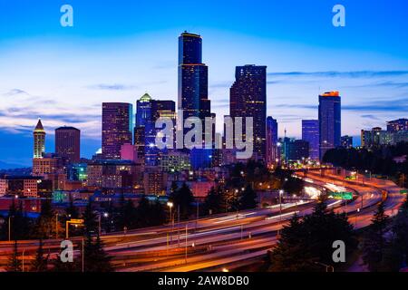 Beleuchteter Blick auf die Innenstadt von Seattle über die Autobahn I5 während der Abenddämmerung vom Dr. Jose Rizal Park, Washington, USA Stockfoto