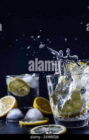 Splash Gin und Tonic Cocktail mit Zitronenscheiben Eiswürfel fällt in Wasser mit Lemonade, Zitronentext Stockfoto
