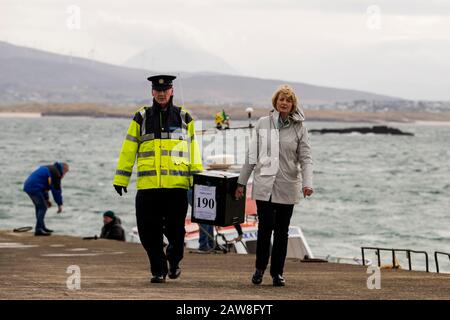 Garda Tom McBride mit Presiding Officer für Gola Island Nancy Sharkey, bereitet sich darauf vor, mit einer Wahlurne auf die Insel vor der Küste von Donegal, Irland, abzureisen, während die Menschen einen Tag vor dem Rest des Landes zu den Umfragen gehen, um ihre Stimme bei der irischen Wahl abzugeben. Stockfoto