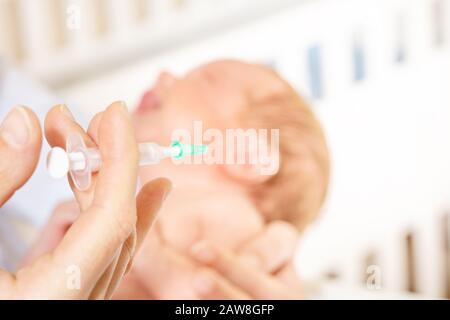 Krankenschwester in einem Krankenhaus halten Sie die Spritze mit Babyjungen Arm weinen während der Impfung im Hintergrund Stockfoto