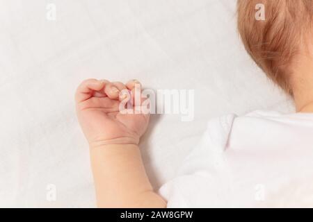 Winzige Nahaufnahme des neugeborenen Säuglings, der auf dem Betttuch liegt Stockfoto