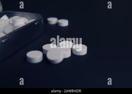 Eine Fülle weißer Pillen in einer Vintage-Metalltin auf dunklem Hintergrund Stockfoto