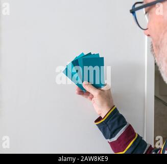 Ein Mann mit verschiedenen Farbfeldern zur Bestimmung der richtigen Farbe der Farbe an einer Wand Stockfoto