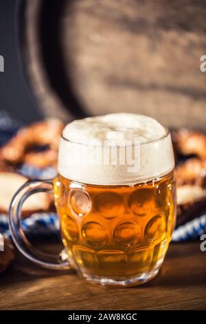 Oktoberfest-Bier mit Bretzel-Holzfass und blauer Tischdecke Stockfoto