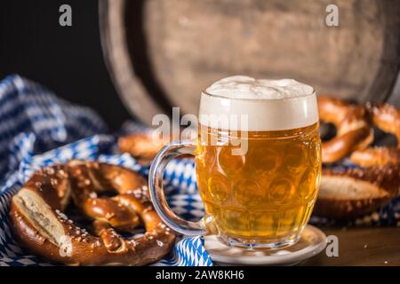 Oktoberfest-Bier mit Bretzel-Holzfass und blauer Tischdecke Stockfoto