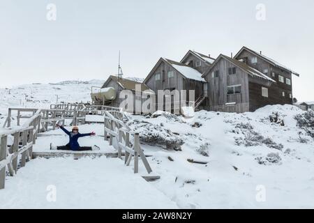 Frauen, die einen Yoga-Aufspaltung machen, posieren im Schnee, in einem Skigebiet in Ben Lomond, Tasmanien, Australien Stockfoto