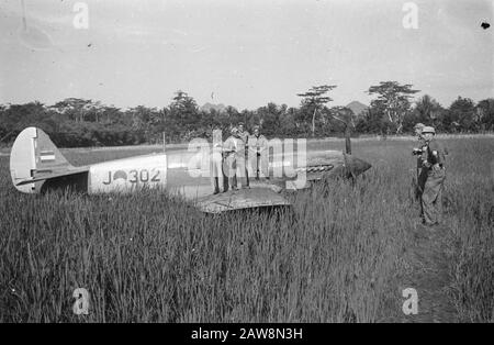 Notlandung eines Curtiss P40 in der Nähe von Solo [niederländische Soldaten sitzen auf einem niederländischen Kampfflugzeug, einer Spitfire, auf einem Reisfeld. Zwei weitere Uhr] Anmerkung: Motor nach dem Tauchangriff während der Beschleunigung abgewürgt; Bauchlandung in einem Paddy-Feld in der Nähe von Poerwakarta gemacht; Telefon schwer beschädigt und abgeschrieben. Ensign Gerard Bruggink ist unverletzt unter [es ist negativ an der falschen Stelle sicher] aus. Datum: 13.März 1949 Ort: Indonesien Niederländisches Ostindien Stockfoto