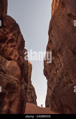 Mädchen, die in einem schmalen Canyon, einer tiefen Schlucht mit senkrechten Wänden, springen. Wadi Rum, Jordanien Stockfoto