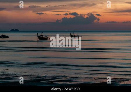 Glorreicher tropischer Sonnenuntergang am Strand von Ao Nang, Provinz Krabi, Thailand, mit zwei langen Schwanzbooten Stockfoto