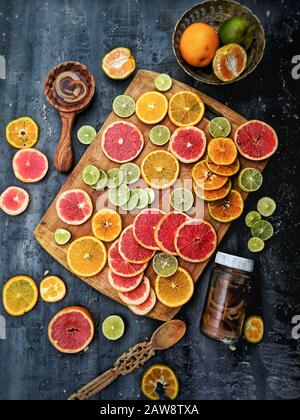 Draufsicht auf gemischte, in Scheiben geschnittene Zitrusfrüchte, mit einem Messer auf einem hölzernen Schneidebrett. Gemischte tropische Früchte (Limette, Zitrone, Orange, Grapefruit), Draufsicht Stockfoto
