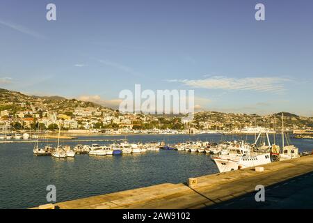 Schöner Blick auf den Hafen mit Segelbooten und Fischerbooten, die an einem sonnigen Tag am Kai und an der Küste vor Anker und festgemacht sind, Sanremo, Ligurien, Italien Stockfoto