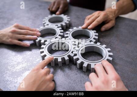 Gruppe von Geschäftsleuten zusammen Gänge verbinden auf Tabelle am Arbeitsplatz Stockfoto