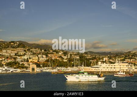 Fischerboote, die in den Hafen einlaufen, sowie Luxusyachten und Segelboote, die im Touristenhafen Porto Sole der Küstenstadt Sanremo, Ligurien, Italien, vergraben sind Stockfoto