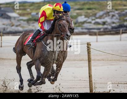 Zwei Jockeys und Rennpferde, die am Strand Rennen Stockfoto