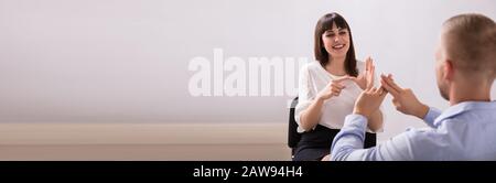 Lächelnde junge Frau und Mann mit Gebärdensprache auf weißem Hintergrund Stockfoto