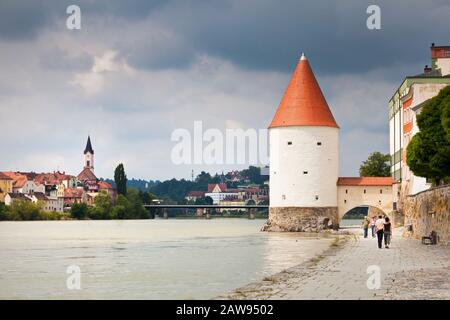 Touristen, die auf dem Flussufer des Inn in Passau, Bayern, Deutschland, in Richtung Schaiblingsturm laufen Stockfoto