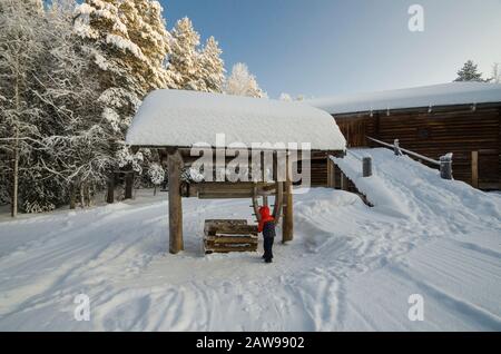 Januar 2020 - Malye Korely. Kleiner Junge an einem Holzbrunnen in einem russischen Dorf. Russland, Region Archangelsk Stockfoto