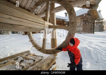 Januar 2020 - Malye Korely. Kleiner Junge an einem Holzbrunnen in einem russischen Dorf. Russland, Region Archangelsk Stockfoto