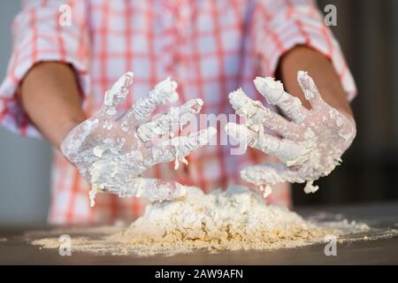 Frau, die ihren Teig bedeckte Hände der Kamera zeigt Stockfoto