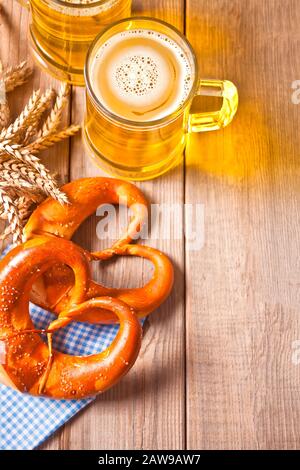 Frisch gebackene bayrische Salz-Brezel mit rwo-Glas Bier auf dem Holztisch. Draufsicht. Kopierbereich. Stockfoto