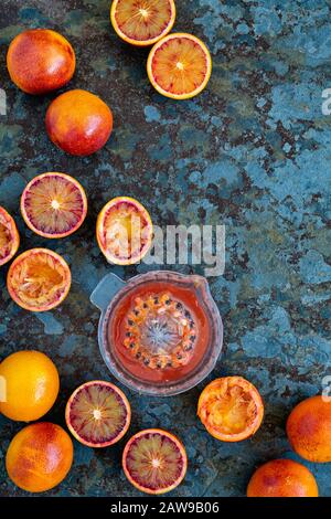 Entsaften von Blutorangen. Orangensaft aus Blut und Orangen aus Blut auf Schiefer Stockfoto